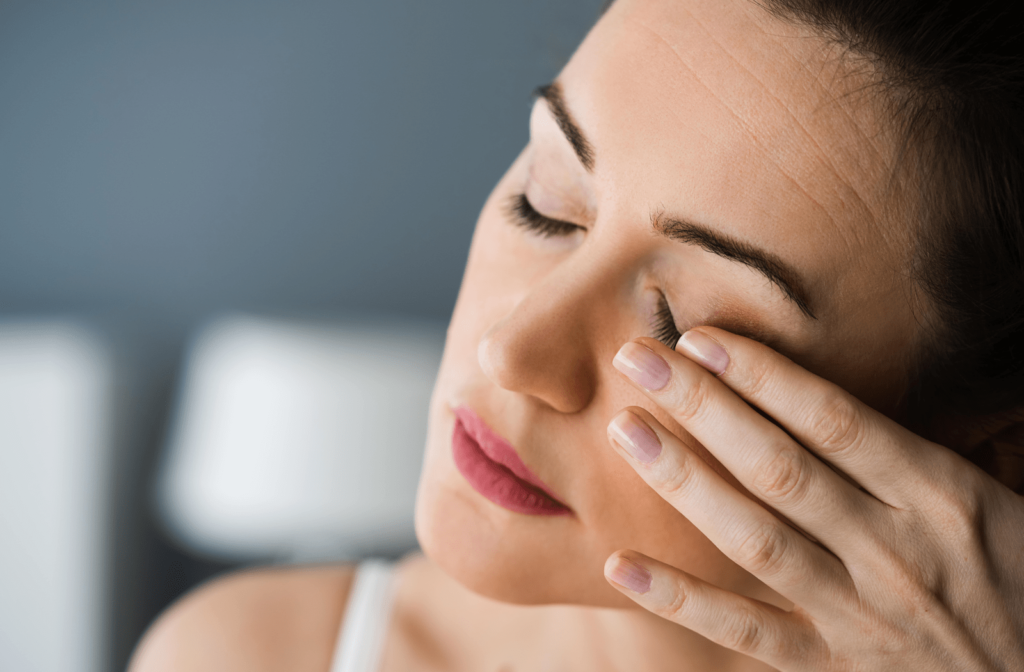 A woman rubs her left eye due to eye pain and strain