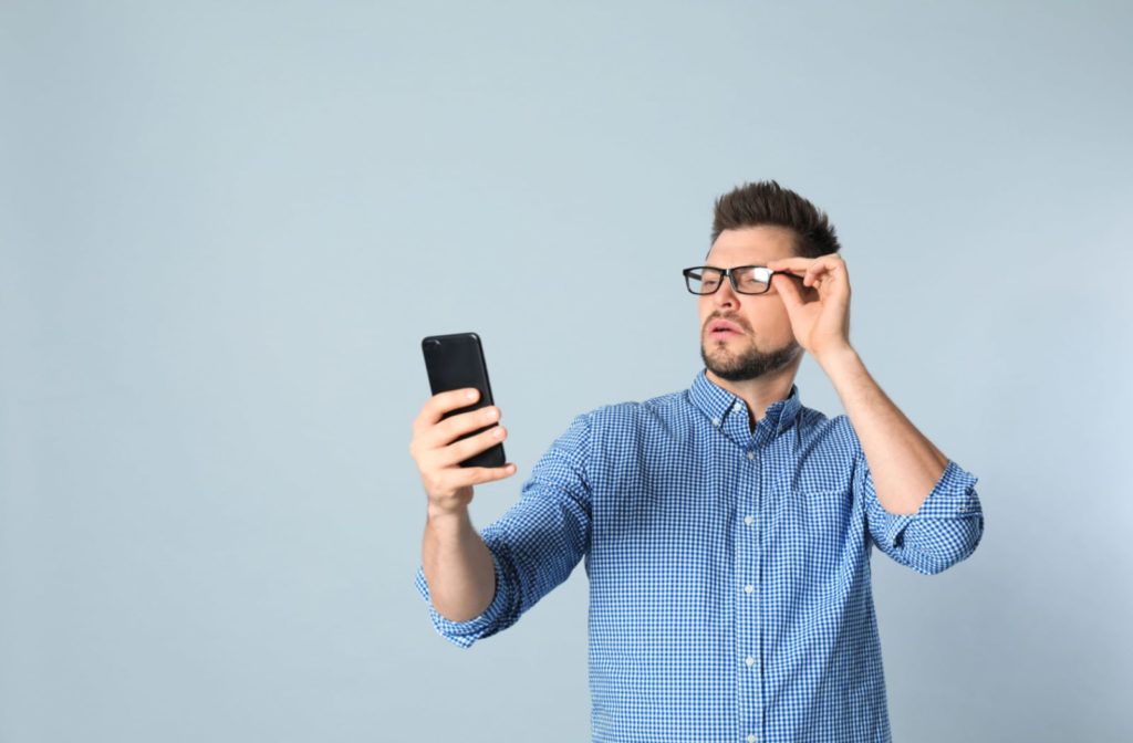 A man struggling to see his phone screen close up - he most likely has hyperopia