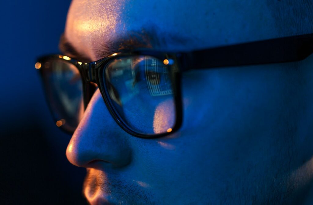A close-up view of a young man wearing glasses with blue light protection.